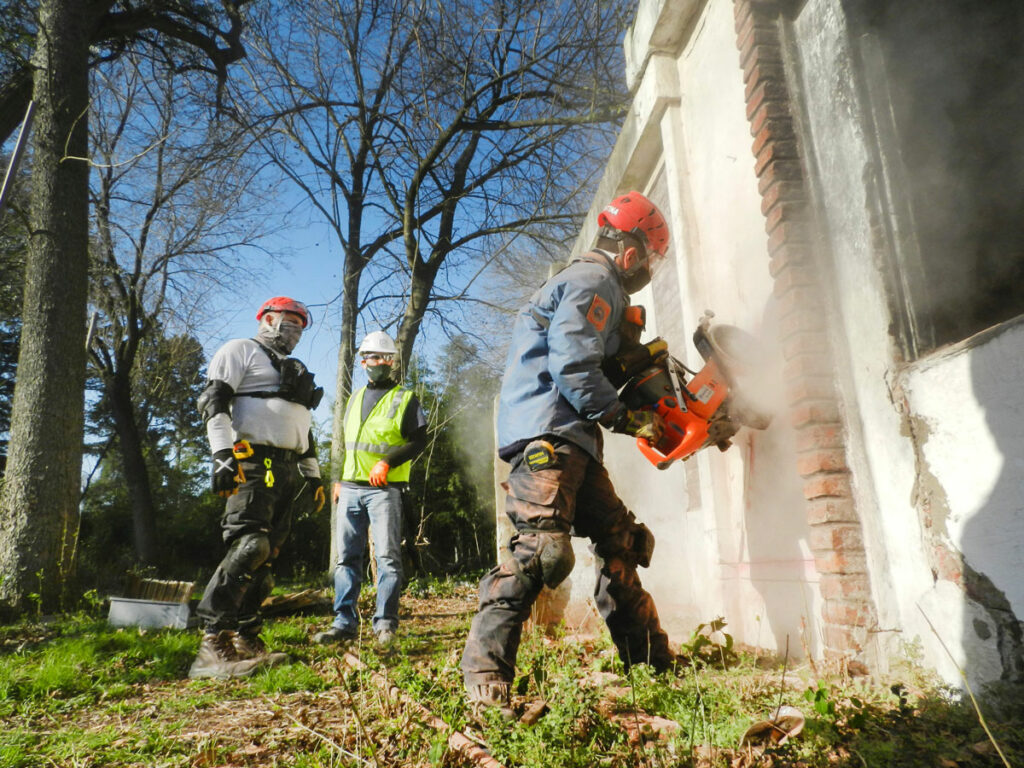 workers with safety gear using a power cutter on a concrete wall