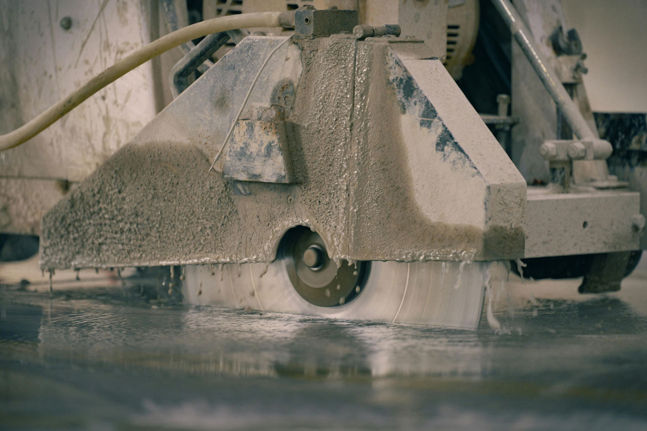 A machine cutting cement on a concrete floor, demonstrating the process of concrete cutting in construction.